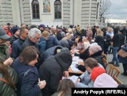 Хмельницкий шіркеуінің алдында петицияға қол қойып жатқан адамдар.