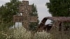 Georgia -- An abandoned car is seen near a cross in the village of Tbeti near Tskhinvali, the capital of the breakaway region of South Ossetia, July 6, 2015