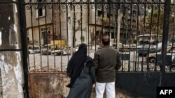 Egypt -- A couple looks at the remains of the ruling National Democratic Party (NDP) headquarters that was burnt during the popular revolt in Cairo, 15Feb2011