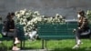 Italy -Women wearing protective face masks chat as they sit on benches in Milan 