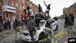 U.S. -- Demonstrators climb on a destroyed Baltimore Police car in the street near the corner of Pennsylvania and North avenues during violent protests following the funeral of Freddie Gray, April 27, 2015