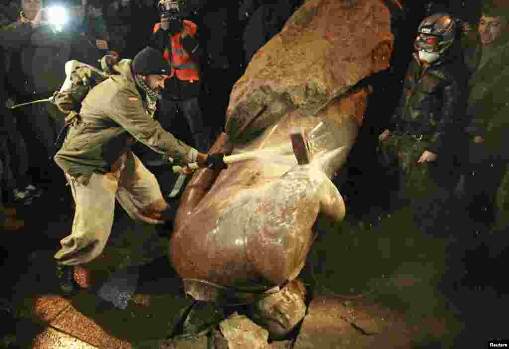 A man smashes a statue of Vladimir Lenin, which was toppled by protesters during a rally in Kyiv.