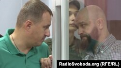 В суде. За стеклом – оправданный обвиняемый Александр Лось